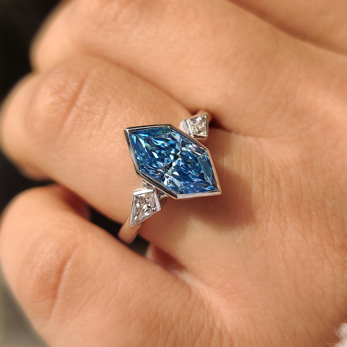 Blue dutch marquise center diamond secured in bezel setting
