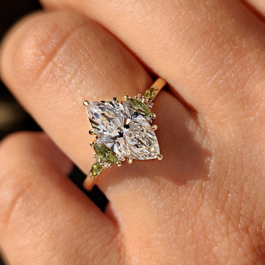 Marquise diamond ring featuring green marquise side stone